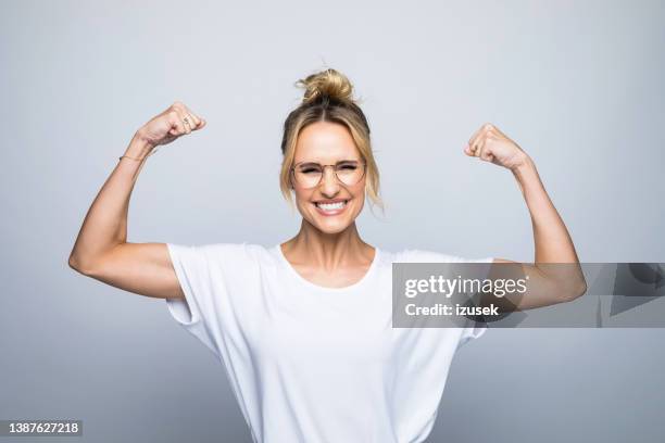 portrait of happy beautiful woman flexing muscle - strong women bildbanksfoton och bilder