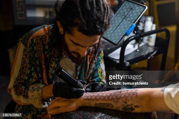 man is tattooing a man's arm - tattooing stock pictures, royalty-free photos & images