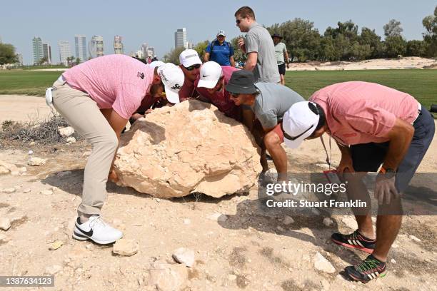 Dean Burmester of South Africa helps move a rock impeding his swing on hole 9 during Day Two of the Commercial Bank Qatar Masters at Doha Golf Club...