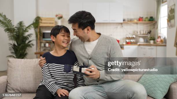 happy surprised asian dad hugging his son after releasing hand covering face and seeing the father’s day gift in the living room at home - s happy days stock pictures, royalty-free photos & images