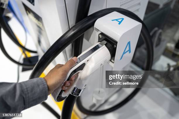 high angle view of human hand holding electric car charger - low carbon technology stockfoto's en -beelden