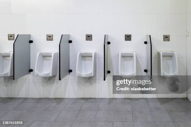 front view of a row of male urinals - bathroom no people stock pictures, royalty-free photos & images