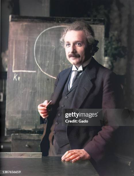 Half-length portrait of scientist Albert Einstein standing at chalkboard, 1921. Note: Image has been digitally colorized using a modern process....