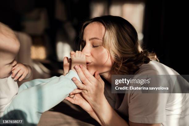 mom kisses the baby's legs. - kissing feet stock pictures, royalty-free photos & images
