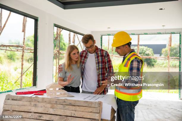 husband and wife consulting with a architect inside a home under construction. - home extension stock pictures, royalty-free photos & images