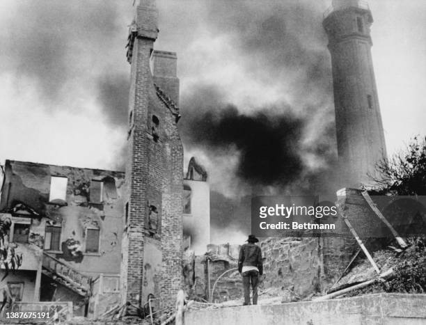 Man stands before a brick section rising above the burned out infirmary on Alcatraz Island where an unchecked blaze burned most of the night and...