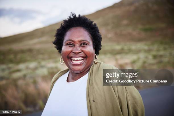 laughing mature woman enjoying a day outdoors in the countryside - black woman laughing stockfoto's en -beelden