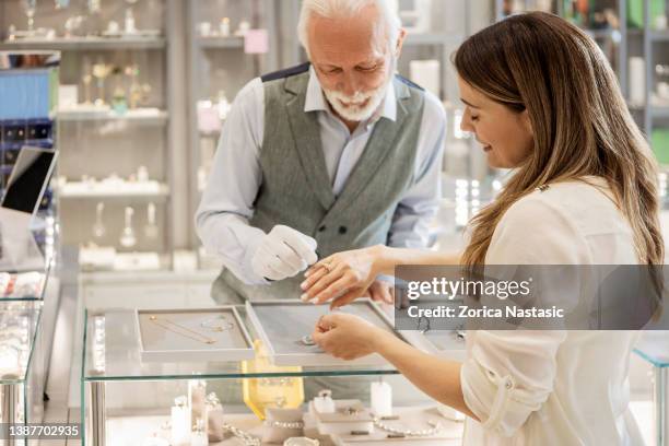 mujer joven probándose un anillo de diamantes - jeweller fotografías e imágenes de stock