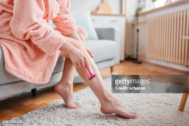 woman in a pink bathrobe shaves her legs - razor blade stock pictures, royalty-free photos & images