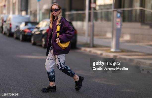 Sonia Lyson seen wearing a yellow Prada iPhone case, Prada yellow triangle leather bag, The Frankie Shop purple berry bomber jacket, Prada black...