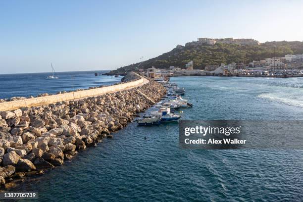 mgarr harbour breakwater on the island of gozo with small boats moored and calm waters at dusk. - mgarr harbour stock pictures, royalty-free photos & images