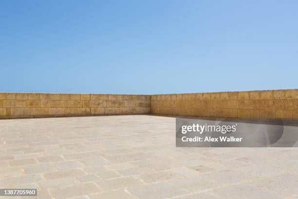 empty courtyard and corner of stone wall with paving stones and clear blue sky - modern malta stock pictures, royalty-free photos & images