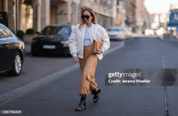 Sonia Lyson seen wearing black Louis Vuitton leather sandals/boots, a Louis Vuitton beige Coussin bag, The Frankie Shop white shiny bomber jacket and...