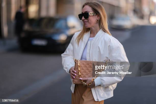 Sonia Lyson seen wearing a Louis Vuitton beige Coussin bag, The Frankie Shop white shiny bomber jacket and The Frankie Shop beige leather pants,...