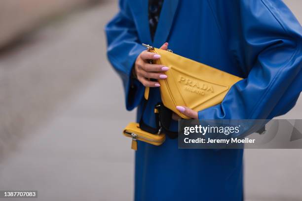 Sonia Lyson seen wearing a Louis Vuitton monogram black and blue top, a blue long leather coat from NA-KD and yellow Prada triangle leather bag on...