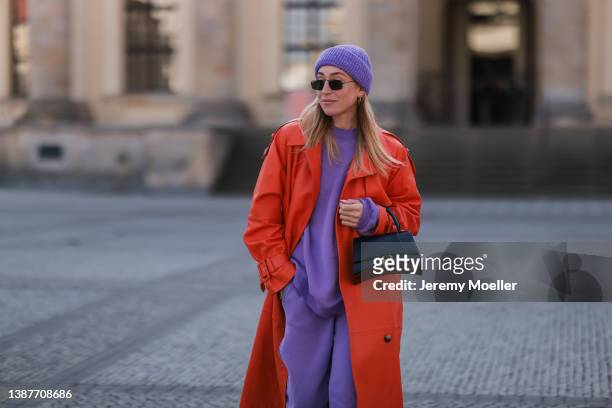 Sonia Lyson seen wearing a purple American Vintage jogger two piece, orange leather coat from Ducie, lilac knit hat from Weekday, Ray Ban sunglasses...