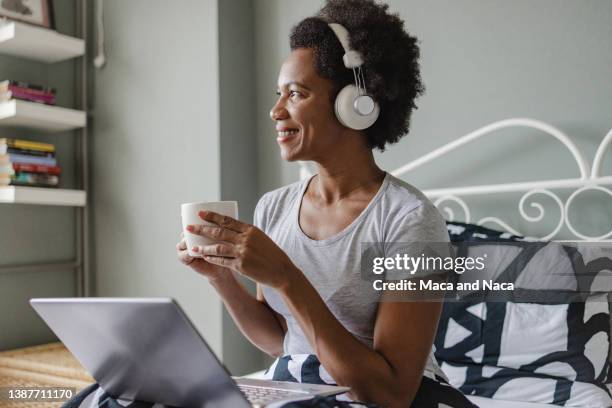 african-american woman is using laptop in bed - african american woman pajamas residential building stock pictures, royalty-free photos & images