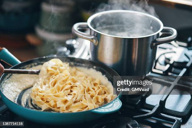 preparing fettuccine pasta alfredo with parmesan - fettuccine alfredo stock pictures, royalty-free photos & images