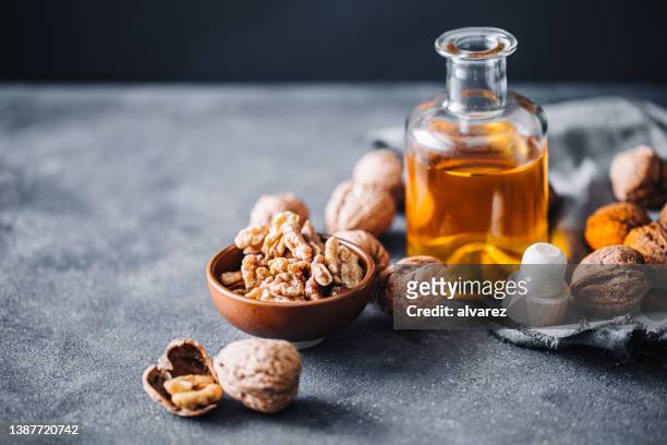 bowl of walnuts and flax seed oil in glass bottle - etherische olie stockfoto's en -beelden