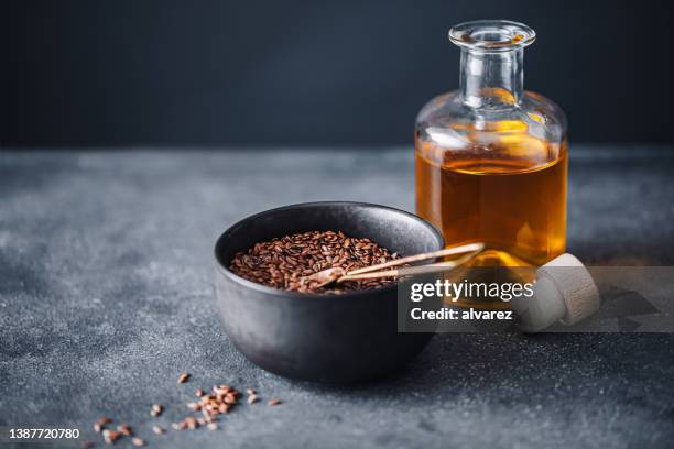 bowl of flax seeds and oil in glass bottle - flax seed stock pictures, royalty-free photos & images