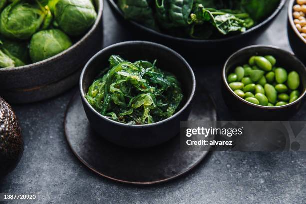 close-up of healthy raw food in bowls on black table - omega 3 stock pictures, royalty-free photos & images