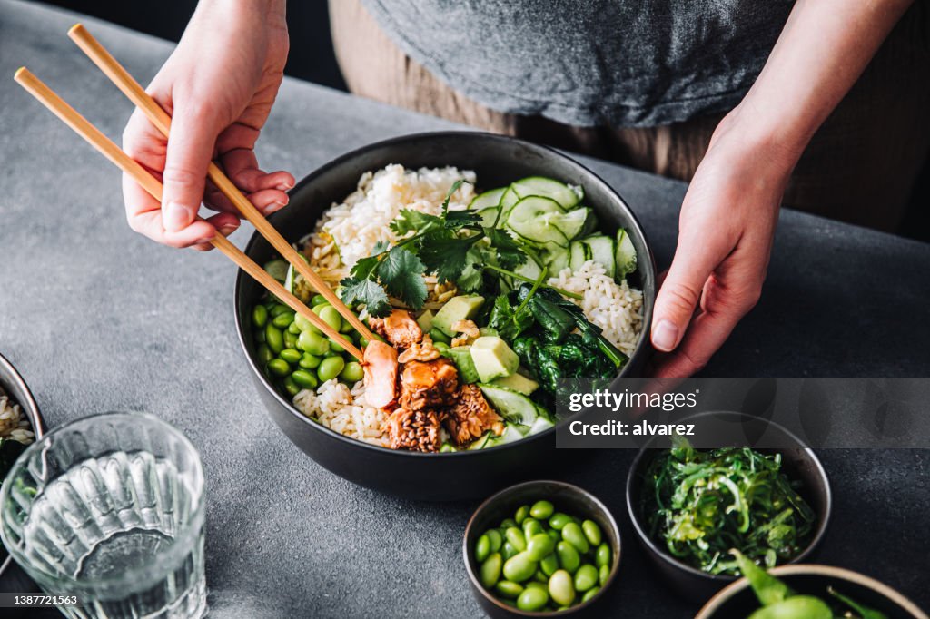 Woman eating poke salad with chopsticks