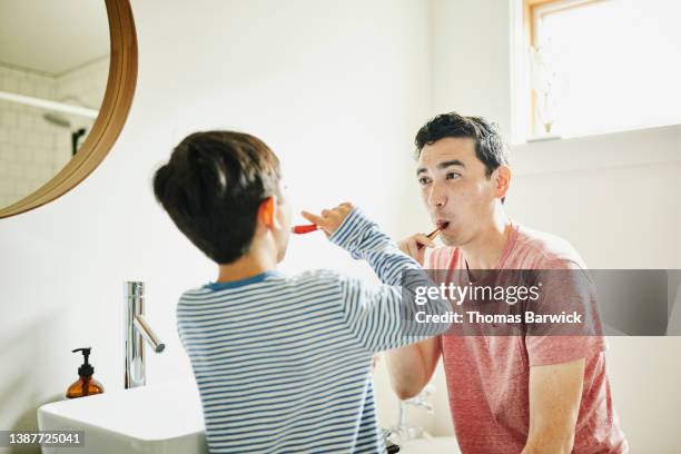 medium shot of father and son brushing teeth in bathroom - brightly lit bathroom stock pictures, royalty-free photos & images