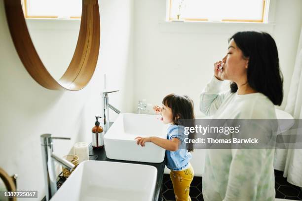 medium shot of mother and daughter brushing teeth in bathroom - american influence stock-fotos und bilder