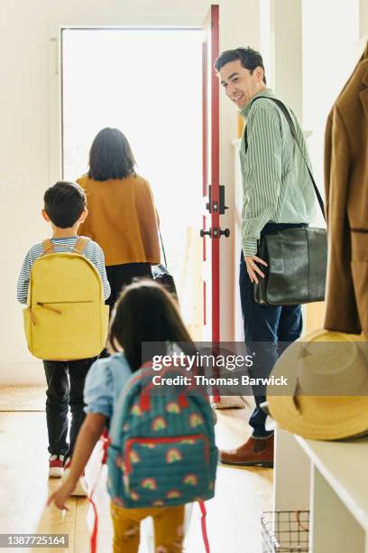 wide shot of family walking out front door to go to work and school - family smiling at front door stock pictures, royalty-free photos & images