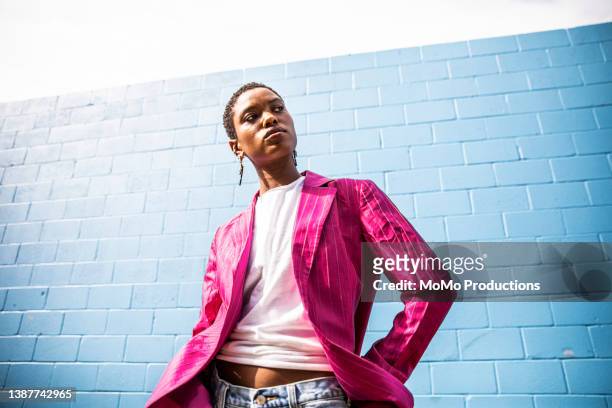 portrait of fashionable young woman in front of bright blue wall - aufnahme von unten frau stock-fotos und bilder