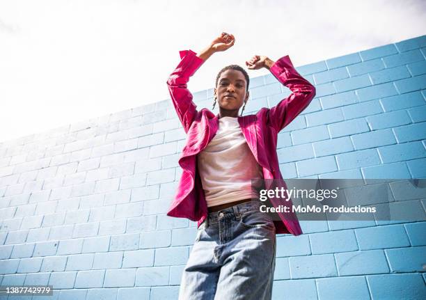 portrait of fashionable young woman in front of bright blue wall - outdoor fashion photography stock pictures, royalty-free photos & images