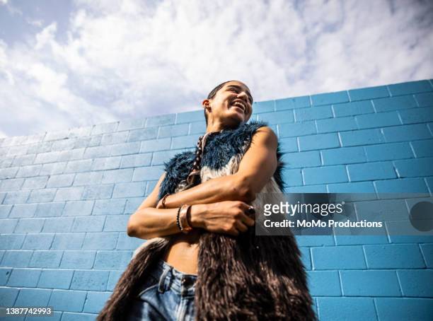 portrait of fashionable young woman in front of bright blue wall - low angle portrait stock pictures, royalty-free photos & images