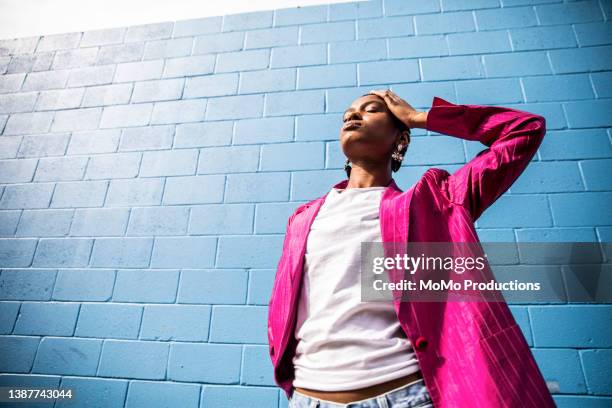 portrait of fashionable young woman in front of bright blue wall - drop earring stock-fotos und bilder