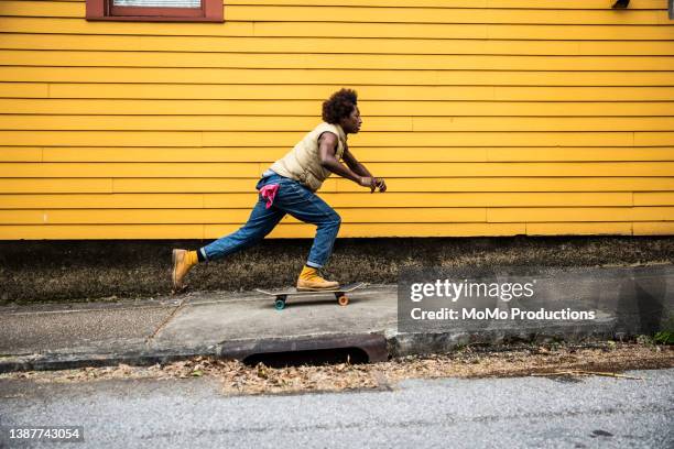 fashionable young man skateboarding in front of yellow urban home - image technique photos et images de collection