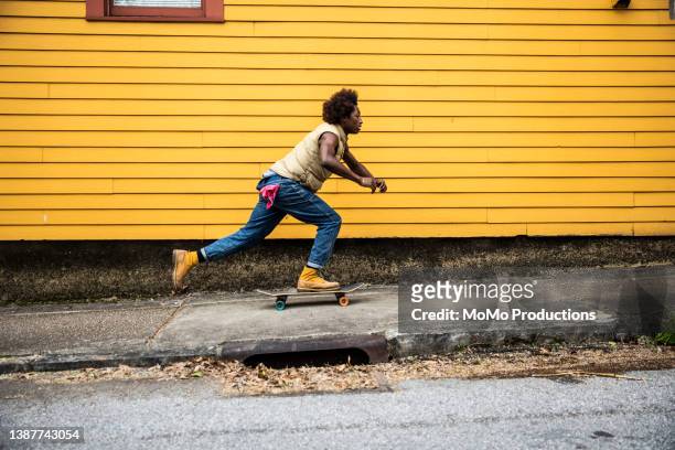 fashionable young man skateboarding in front of yellow urban home - street style men stock pictures, royalty-free photos & images