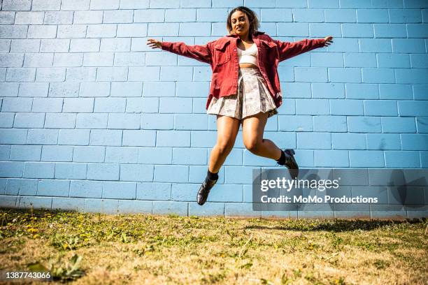 portrait of fashionable young woman in front of bright blue wall - red skirt stock pictures, royalty-free photos & images