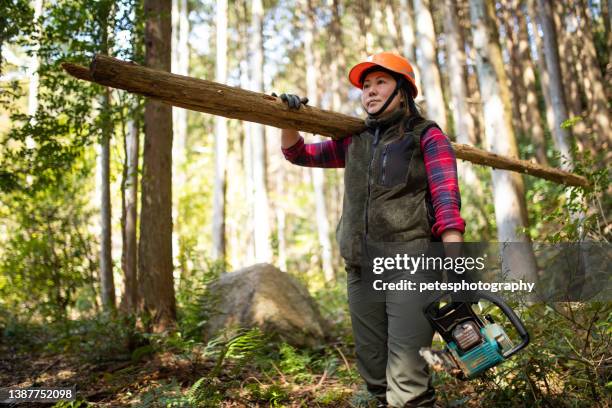 a female lumberjack carrying logs through forest - lumberjack stock pictures, royalty-free photos & images