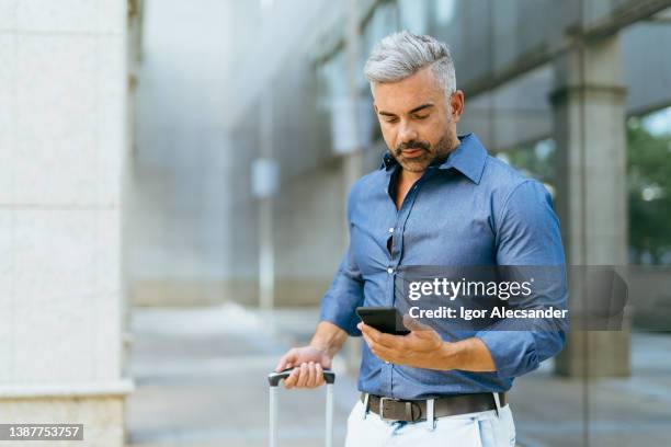businessman with rolling suitcase in the financial district - barra da tijuca stock pictures, royalty-free photos & images