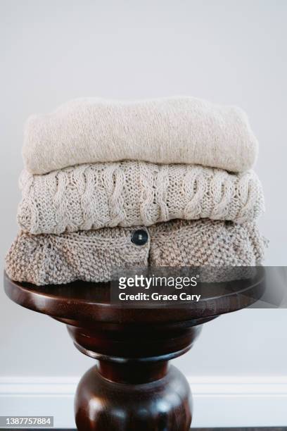 stack of beige knit sweaters folded on table - la casa imagens e fotografias de stock