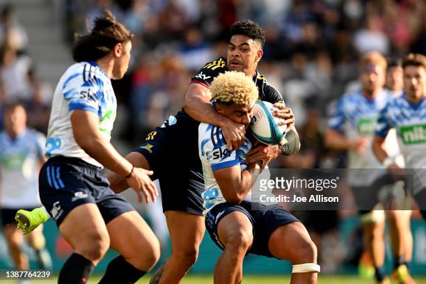 Hoskins Sotutu of the Blues is tackled by Fetuli Paea of the Highlanders during the round six Super Rugby Pacific match between the Highlanders and...