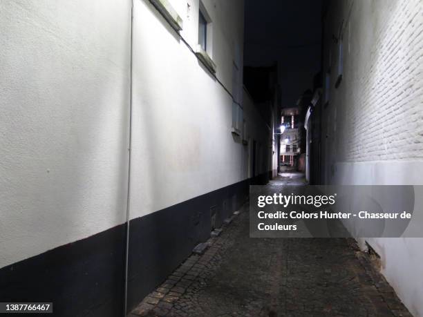 a cobblestone alley at night with white walls and diminishing perspective with no people in brussels - wall night stock-fotos und bilder