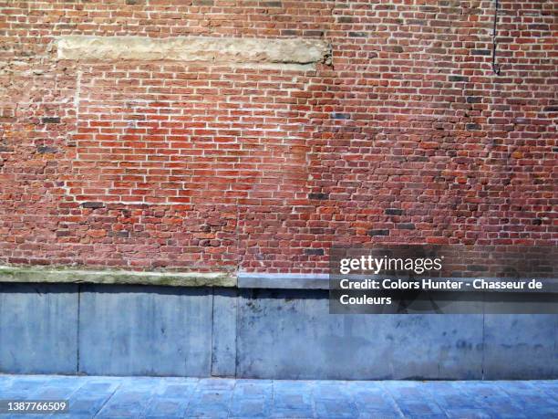 weathered brick and gray stone wall with sidewalk under urban lighting in brussels - wall night stock-fotos und bilder
