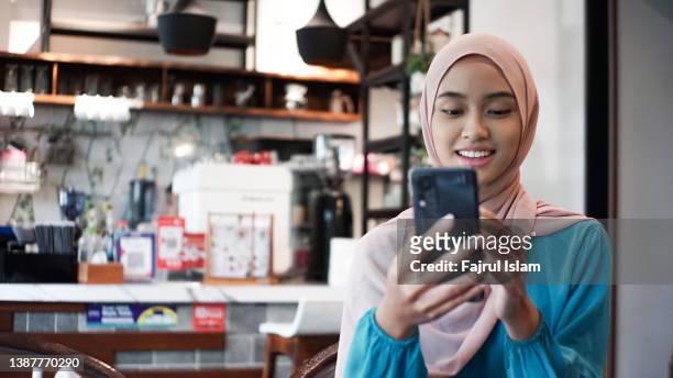 young woman using smartphone for teleconferencing - indonesia women stockfoto's en -beelden