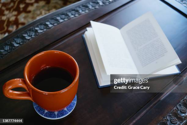 mug and book on coffee table - coffee table books stockfoto's en -beelden