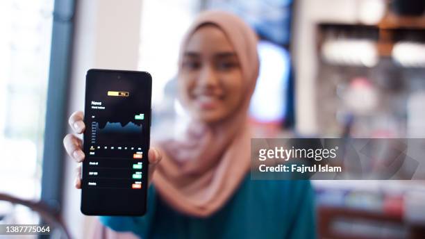 hijab woman invest online stocks trading on mobile platform app - trading screen stock-fotos und bilder