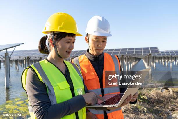 close-up of male and female engineers discussing work at solar power plant - green economy stock pictures, royalty-free photos & images