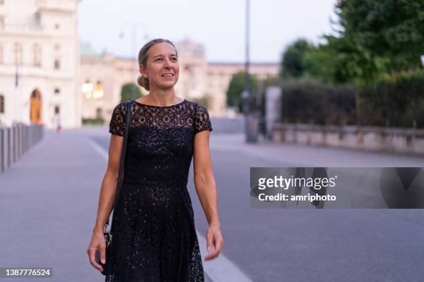 woman in black dress walking through city of vienna - cocktail dress stock pictures, royalty-free photos & images
