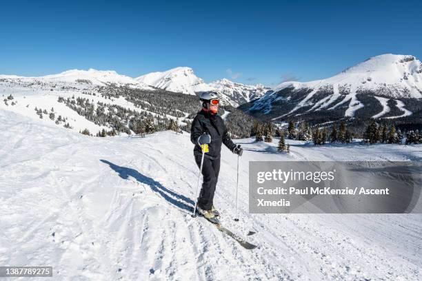 female skier relaxes on snowy mountain ridge - banff ski stock pictures, royalty-free photos & images