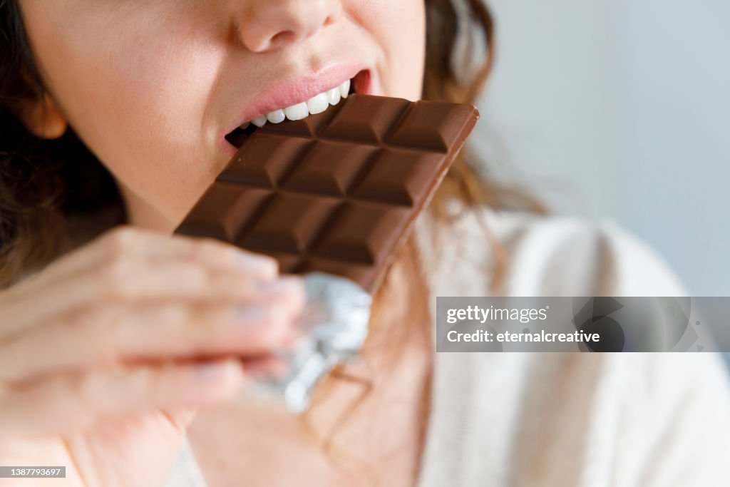 Femme mordant une barre de chocolat