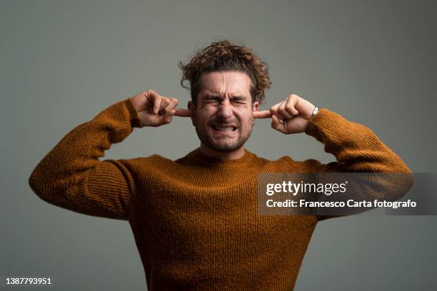 man covering his ears - vingers in de oren stockfoto's en -beelden